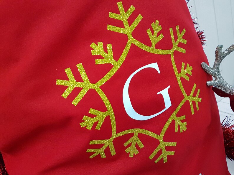May include: Red fabric stocking with a gold glitter snowflake and the letter "G" in white.