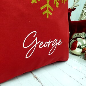May include: Red Christmas stocking with a gold glitter snowflake and the name "George" embroidered in white.