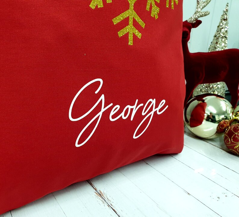May include: Red Christmas stocking with a gold glitter snowflake and the name "George" embroidered in white.