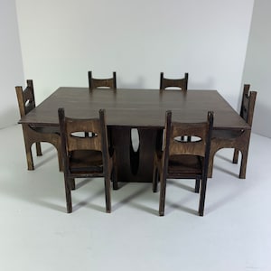 May include: A dark brown wooden dining table set with six chairs. The table has a rectangular top and a simple design. The chairs are also made of dark brown wood and have a simple, modern design.