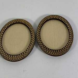 Puede incluir: Dos posavasos redondos de madera con un borde decorativo. Los posavasos son sin terminar y tienen un color de madera natural.