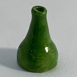 Op de afbeelding: Een kleine, groene keramische vaas met een ronde basis en een smalle hals.