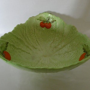 May include: A green ceramic salad bowl shaped like a lettuce leaf with three red tomatoes painted on the rim.