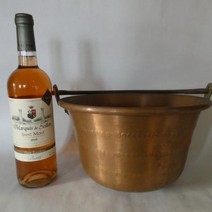 May include: A copper bucket with a wooden handle and a bottle of rose wine labeled "Marquis de Seillan Saint Mont 2019".