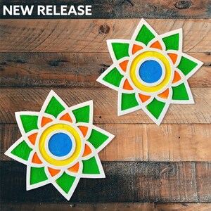 May include: Two colorful, star-shaped, paper cutouts with concentric circles in shades of green, orange, yellow, and blue. The cutouts are on a wood background.
