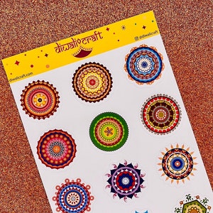 May include: A sheet of colorful mandala stickers with a white background. The stickers feature intricate designs in various colors, including red, blue, green, yellow, and orange. The sheet is labeled "Diwali Craft" and includes the website "diwalicraft.com".