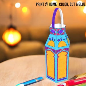 Op de afbeelding: Een blauwe en oranje papieren lantaarn met een paarse handgreep. De lantaarn heeft een halve maan en ster ontwerp. De tekst "PRINT @ HOME: COLOR, CUT & GLUE" is zichtbaar bovenaan de afbeelding.