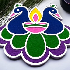 May include: A colorful sand art design featuring two peacocks facing each other with their tails spread out in a flower shape. The peacocks are blue, the flower is green, purple, and pink.
