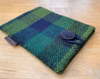 May include: A green and blue plaid fabric phone case with a black button and a brown leather tag that says "Nathan Designs".