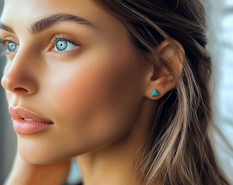 Könnte beinhalten: Nahaufnahme eines Frauen Gesichts mit langen braunen Haaren. Sie trägt einen kleinen türkisfarbenen Dreiecks-Ohrring.