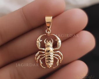 Könnte beinhalten: Goldfarbener Skorpion-Anhänger. Der Skorpion ist mit strukturierten Linien verziert und hat ein erhabenes Design.