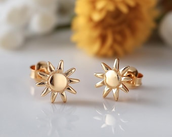 Peut inclure: Une paire de boucles d'oreilles en forme de soleil en or. Les boucles d'oreilles sont petites et délicates, avec un design simple de soleil.