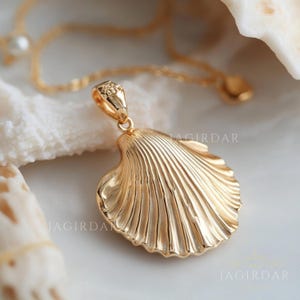 May include: Gold seashell pendant necklace. The pendant is a detailed, realistic depiction of a seashell with a textured surface. The necklace is a delicate chain.