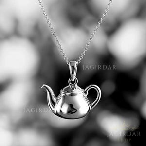 May include: A silver teapot pendant necklace. The teapot is detailed and has a shiny finish. The necklace is on a silver chain.
