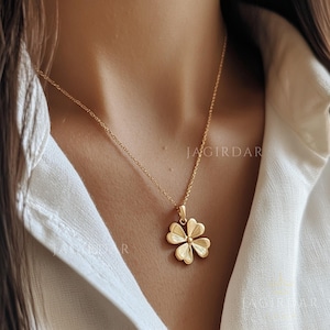 Peut inclure: Un collier en chaîne dorée avec un pendentif en forme de trèfle à quatre feuilles. Le trèfle est détaillé avec un design texturé.