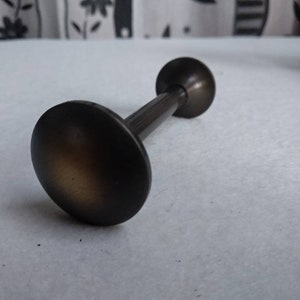 Puede incluir: Un terminal de barra de cortina de metal marrón oscuro con una parte superior redondeada.