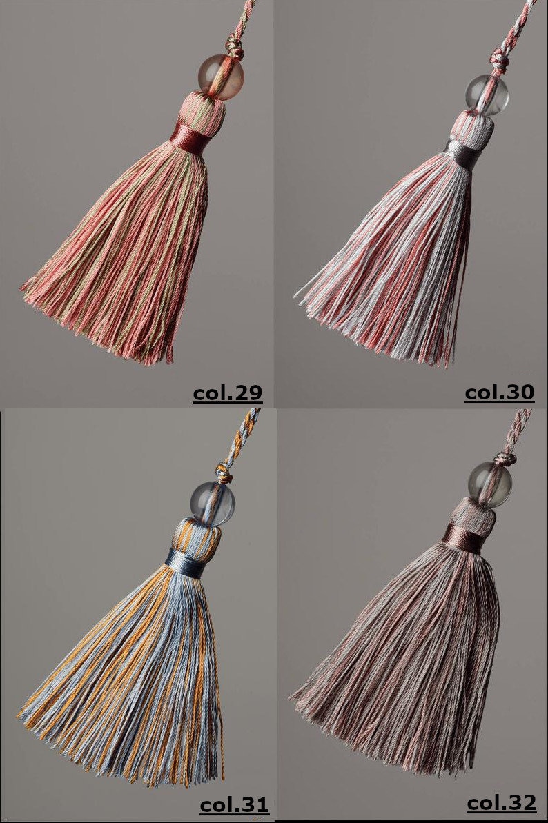May include: Four different coloured tassels with a clear glass bead at the top. The tassels are made of a striped fabric in shades of pink, white, blue, and brown.