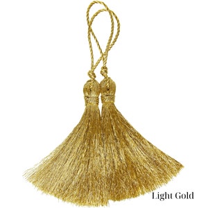 Op de afbeelding: Twee gouden kwastvormbindingen in een licht gouden kleur.