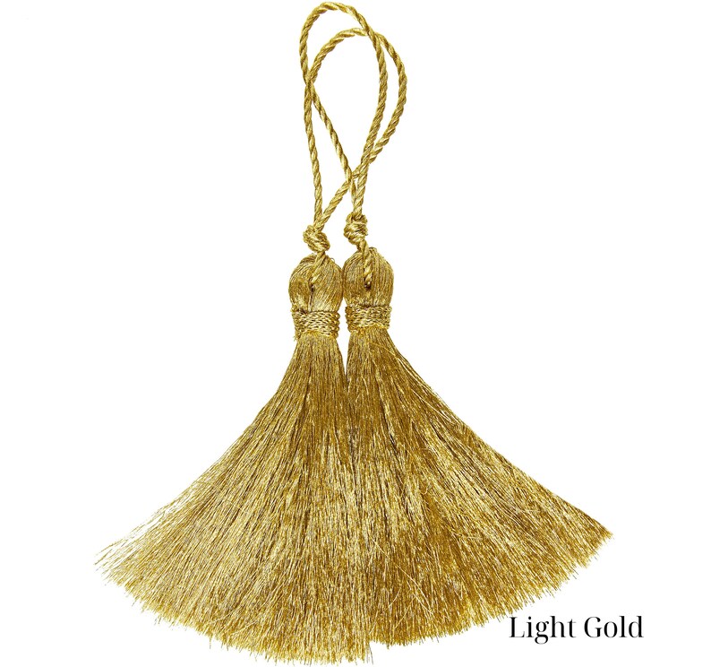 Op de afbeelding: Twee gouden kwastvormbindingen in een licht gouden kleur.