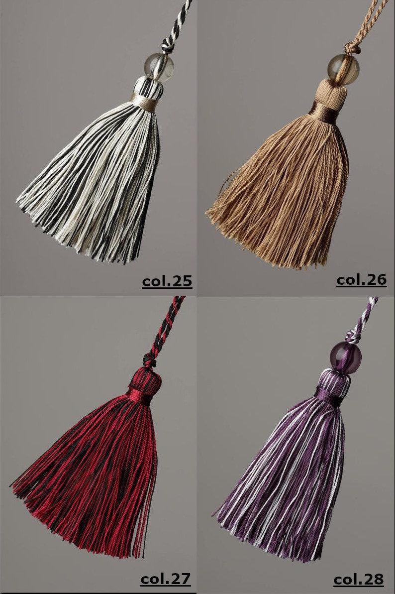 May include: Four different coloured tassels with a decorative bead at the top. The tassels are black and white, brown, red and black, and purple and white.
