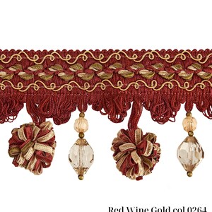 May include: Decorative trim in red wine and gold. The trim features a woven design with gold accents, tassels, and decorative beaded pendants. The text "Red Wine Gold col 0264" is printed at the bottom. This trim is suitable for home decor and craft projects.