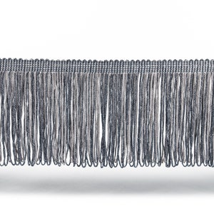 Puede incluir: Una cinta de flecos plateada y negra con textura tejida. Los flecos miden aproximadamente 2,5 cm de largo.
