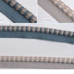 May include: Two samples of trim fabric, one in a light blue color and the other in a light beige color. Both trims feature a decorative edge with small, round, beige and brown woven balls.