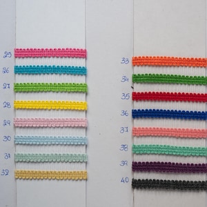 May include: A display of colorful decorative trim samples. The samples are arranged on white cards and include various colors such as pink, turquoise, green, yellow, and blue. Additional colors include orange, red, navy, coral, teal, purple, and black.
