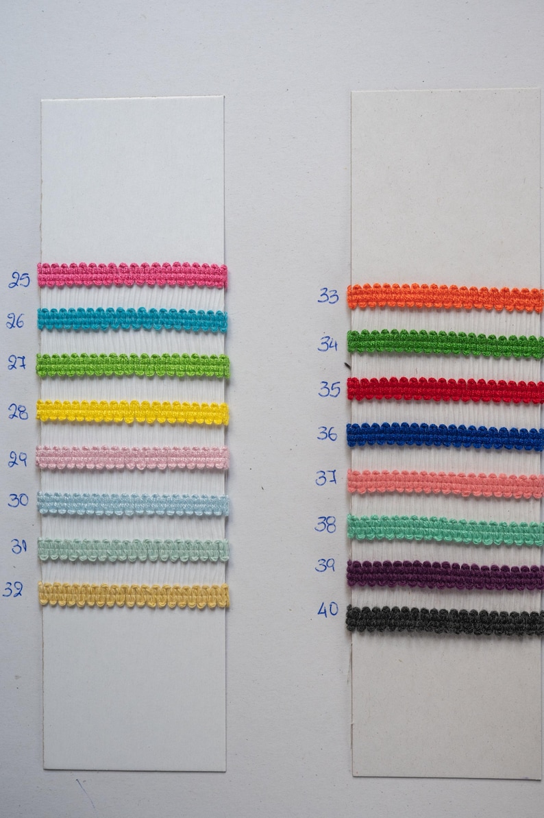 May include: A display of colorful decorative trim samples. The samples are arranged on white cards and include various colors such as pink, turquoise, green, yellow, and blue. Additional colors include orange, red, navy, coral, teal, purple, and black.