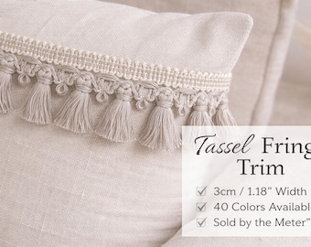 Peut inclure: Gros plan d'un coussin beige avec une bordure décorative à franges et pompons. La bordure mesure 3 cm de large et comporte de petits pompons. L'image contient le texte "Tassel Fringe Trim".