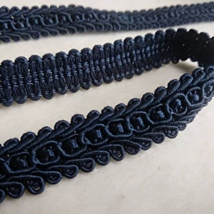 May include: A close-up of dark blue trim with a decorative, woven pattern. The trim is made of a soft, pliable material and has a slightly textured surface.
