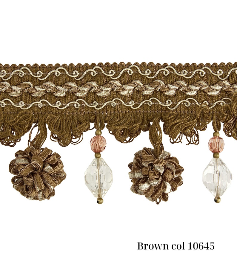 May include: Brown decorative trim with a textured design, featuring a woven top section with a wavy pattern and a fringe of tassels. Clear, faceted beads and pink beads hang from the trim. The text "Brown col 10645" is at the bottom.
