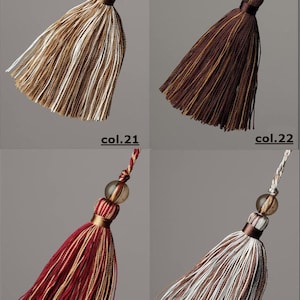 May include: Four different coloured tassels with a brown bead at the top. The tassels are brown and white, brown, red and white, and white and brown.