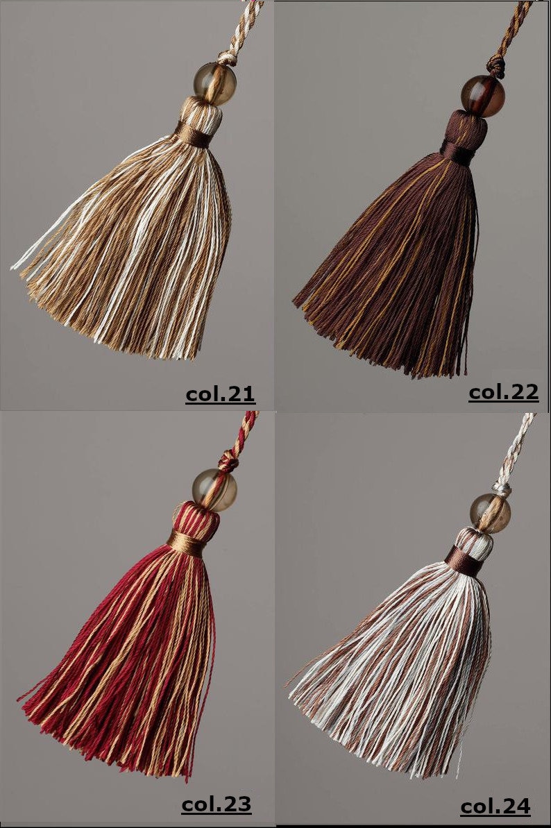 May include: Four different coloured tassels with a brown bead at the top. The tassels are brown and white, brown, red and white, and white and brown.