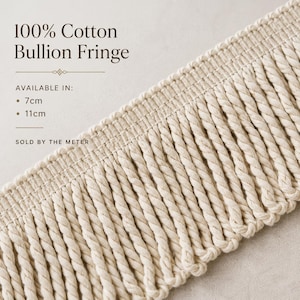Op de afbeelding: Close-up van een crèmekleurige 100% katoenen bullion franje. De tekst luidt "100% Cotton Bullion Fringe" en "Verkrijgbaar in: 7cm, 11cm". De franje wordt per meter verkocht.