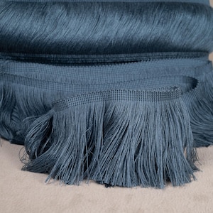 Peut inclure: Un rouleau de galon à franges bleu sarcelle avec une texture tissée. La frange mesure environ 2,5 cm de long.