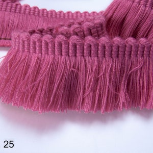May include: Pink fringe trim with a woven top edge. The fringe is about 1 inch long. Col. 25