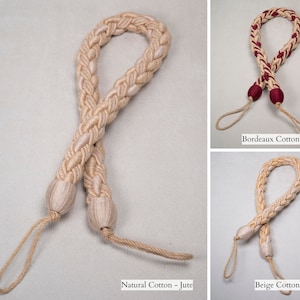 May include: Three braided rope curtain tiebacks in different colors: natural, beige, and burgundy. Each tieback has a loop at the top and two tassels at the bottom. The text "Natural Cotton - Jute", "Beige Cotton - Jute", and "Bordeaux Cotton - Jute" is visible below each tieback.