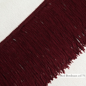 May include: Red Bordeaux fringe trim with a 75 mm width. The fringe is made of a soft, silky material and has a deep red colour.