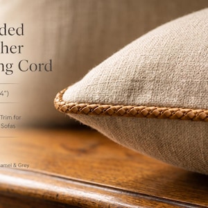 May include: A tan braided leather piping cord trim measuring 6mm (0.24 inches) in diameter, attached to the edge of a beige linen cushion. The text on the image reads Braided Leather Piping Cord, 6mm (0.24"), Upholstery Trim for Cushions & Sofas.