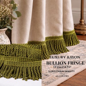 Peut inclure: Un rideau en tissu beige avec une épaisse frange bullion vert olive sur le bord inférieur. Le texte sur l'image indique : LUXURY RAYON BULLION FRINGE, 11 cm / 4.33", 3 OR 5 CHAIN DENSITY, 65 COLORS. La frange est composée de cordons torsadés.