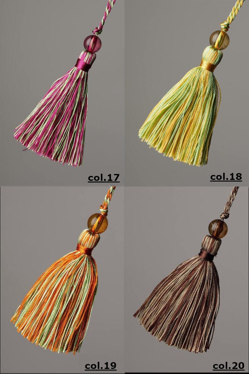 May include: Four different coloured tassels with beads. The tassels are made of a striped fabric and have a fringe at the bottom. The beads are clear and have a slight amber colour. The tassels are labelled with the numbers 17, 18, 19, and 20.