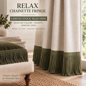 May include: Off-white fabric curtain and a matching cushion, both featuring a deep olive green chainette fringe trim. The text on the image reads: RELAX CHAINETTE FRINGE, LIMITED STOCK SELECTION, SELECTED COLORS, HEIGHTS, LENGTHS ONLY, READY TO SHIP, SOLD BY THE METER, Timeless Details for Beautiful Spaces.
