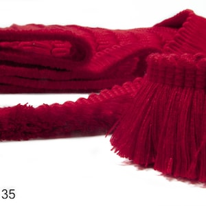 Puede incluir: Borde de flecos rojo con un borde tejido texturizado. El fleco está hecho de fibras suaves y esponjosas. Col. 35