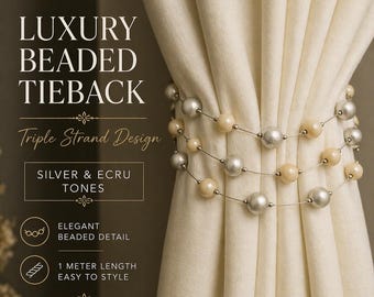 May include: A triple-strand beaded tieback in silver and ecru tones, wrapped around a cream curtain. The tieback has silver and cream-colored beads. The image text reads "Luxury Beaded Tieback" and "1 meter length".