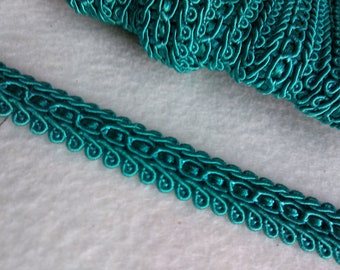 May include: Teal blue decorative trim with a repeating pattern of small loops and swirls.