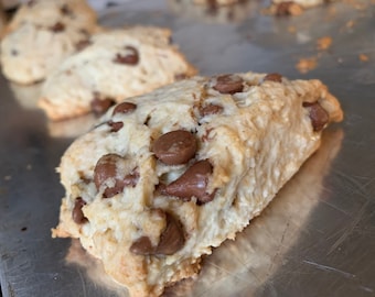 May include: Close-up of a freshly baked scone with chocolate chips on a silver baking sheet.