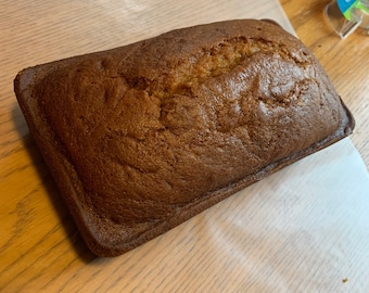 May include: A loaf of freshly baked bread in a loaf pan. The bread is golden brown and has a slightly crusty exterior.