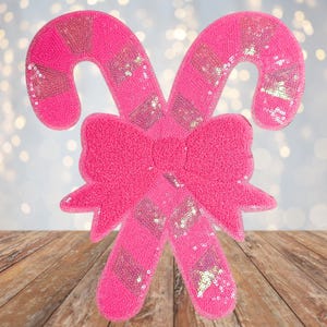 May include: Pink candy cane Christmas ornament with a sparkly finish and a pink bow.