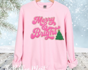 May include: Pink sweatshirt with a fuzzy pink and brown "Merry & Bright" design with a green Christmas tree.